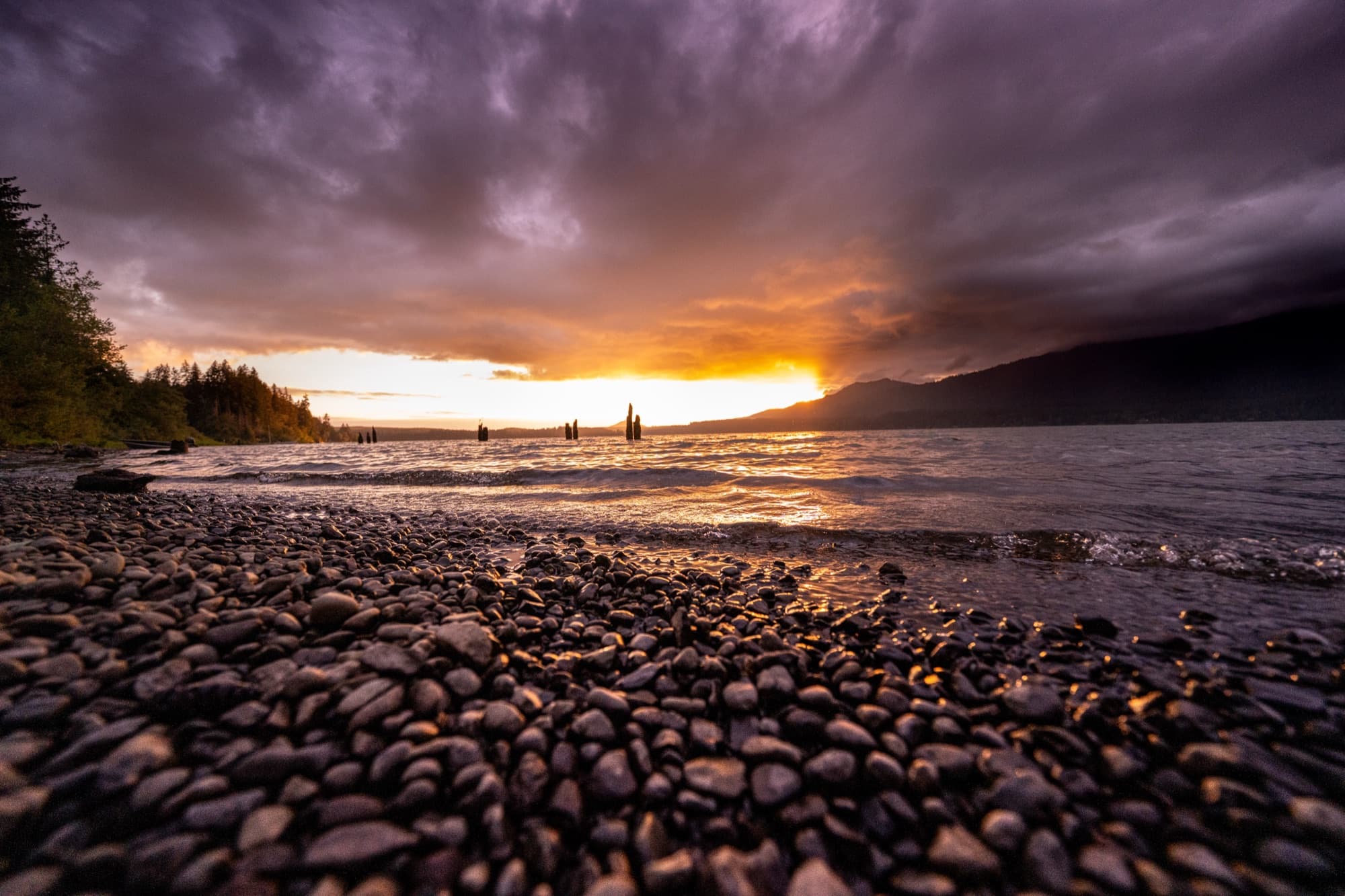 Storm-lit sunset over a pebble beach shoreline